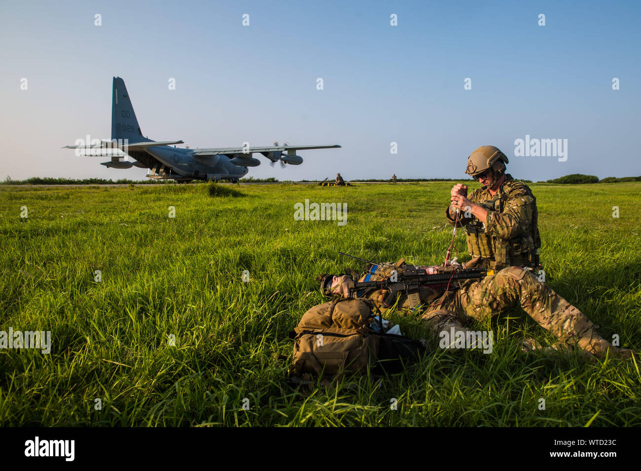 An Air Force medical technician with the 353rd Special Operations Group provides medical attention to a simulated casualty during a simulated airfield seizure after a long-range raid from the amphibious assault ship USS Wasp (LHD 1) at Ie Shima Training Facility, Okinawa, Japan, Aug. 12, 2019 The 31st MEU and Amphibious Squadron 11, aboard Wasp Amphibious Ready Group ships, conducted a series of sequential operations which simulated naval expeditionary combined-arms maneuver from amphibious assets to shore, utilizing Marine Air-Ground Task Force capabilities integrated across all warfighting d Stock Photo