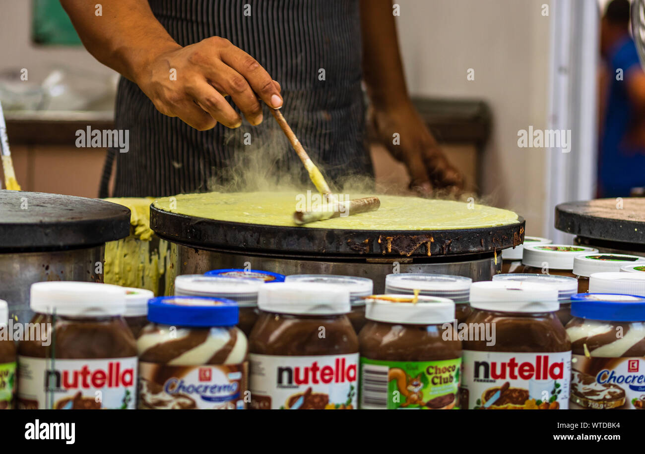 Chefs making and selling crepes, pancakes at a food festival in