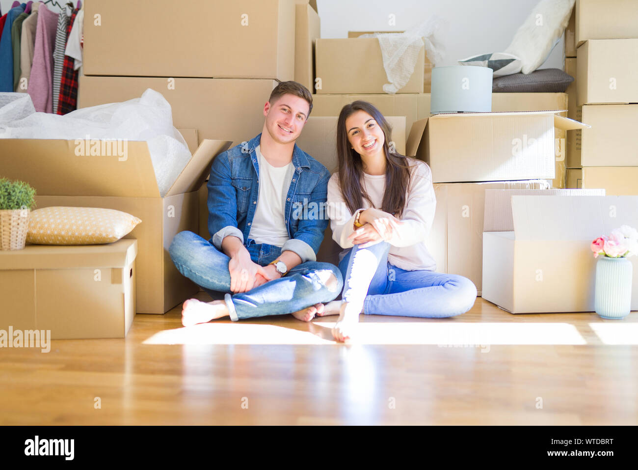 Young beautiful couple relaxing sitting on the floor around cardboard