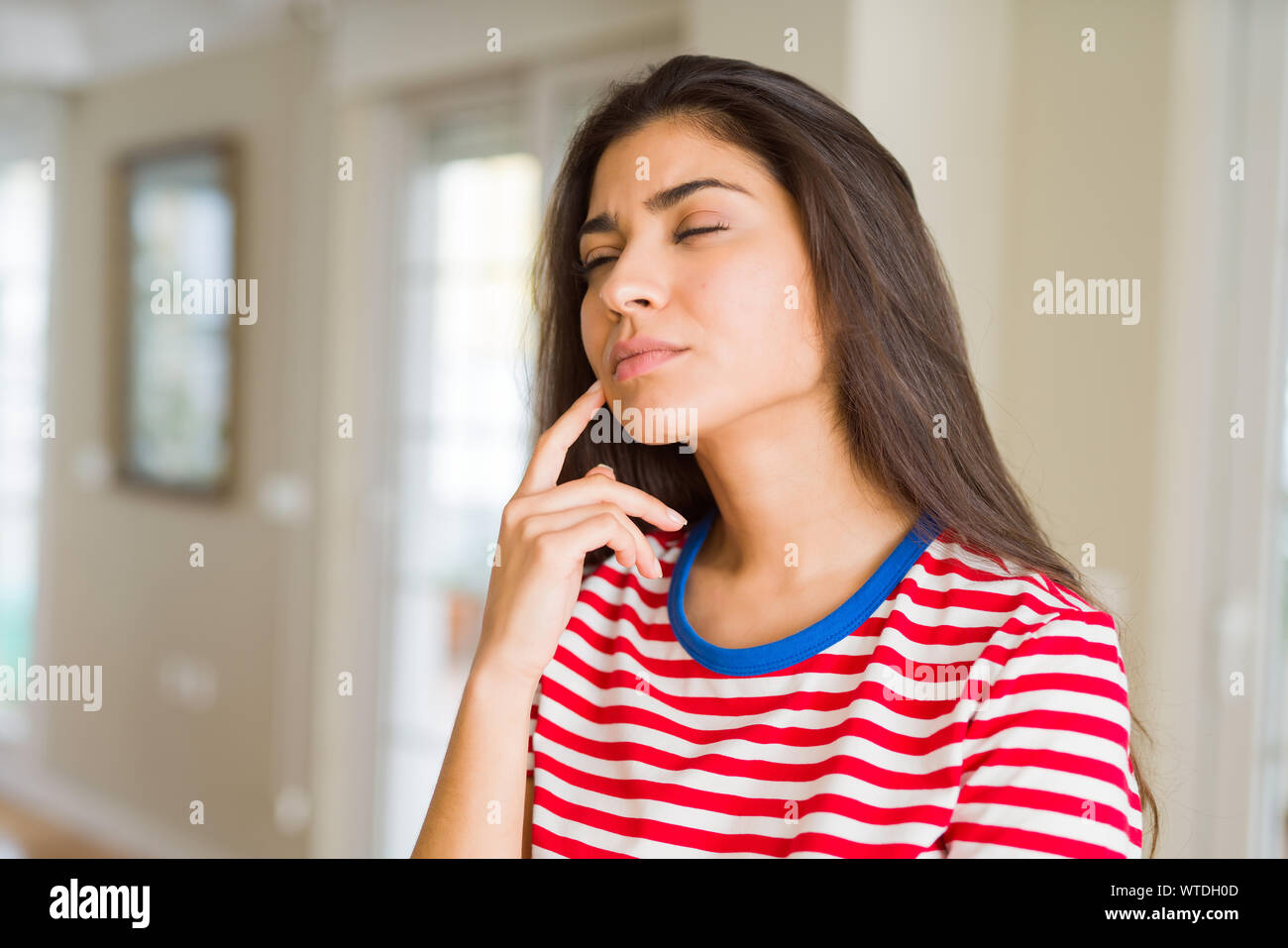 Young beautiful woman thinking and wondering with a hand on chin, doubt concept Stock Photo