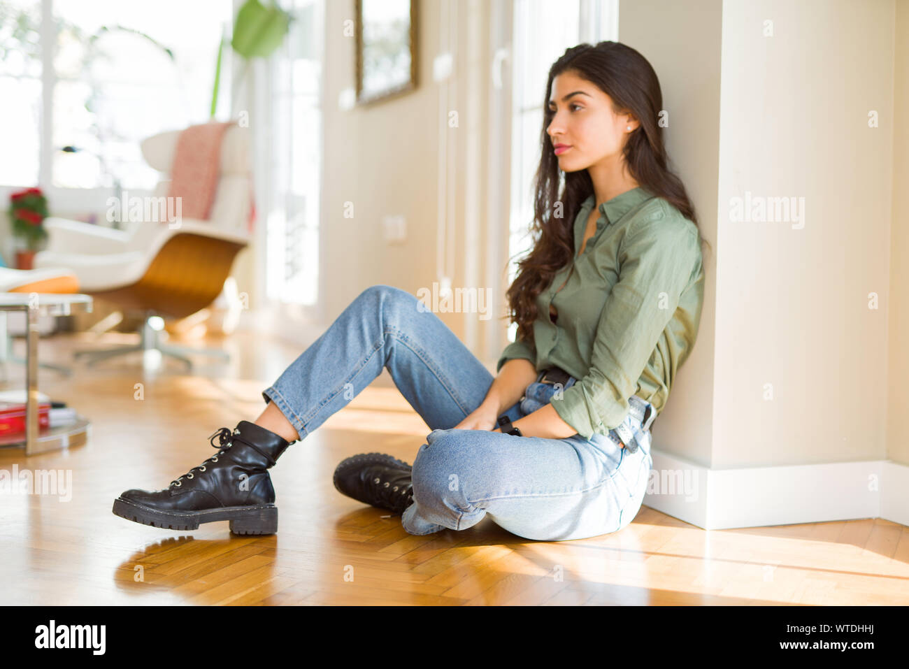 Young beautiful woman sitting on the floor at home looking to side, relax  profile pose with natural face with confident smile Stock Photo - Alamy