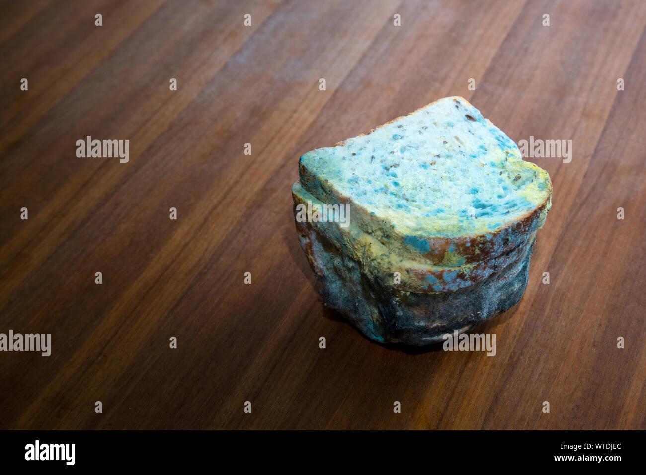 Loaf of rotten, moldy sliced bread on wooden table, space for text Stock Photo