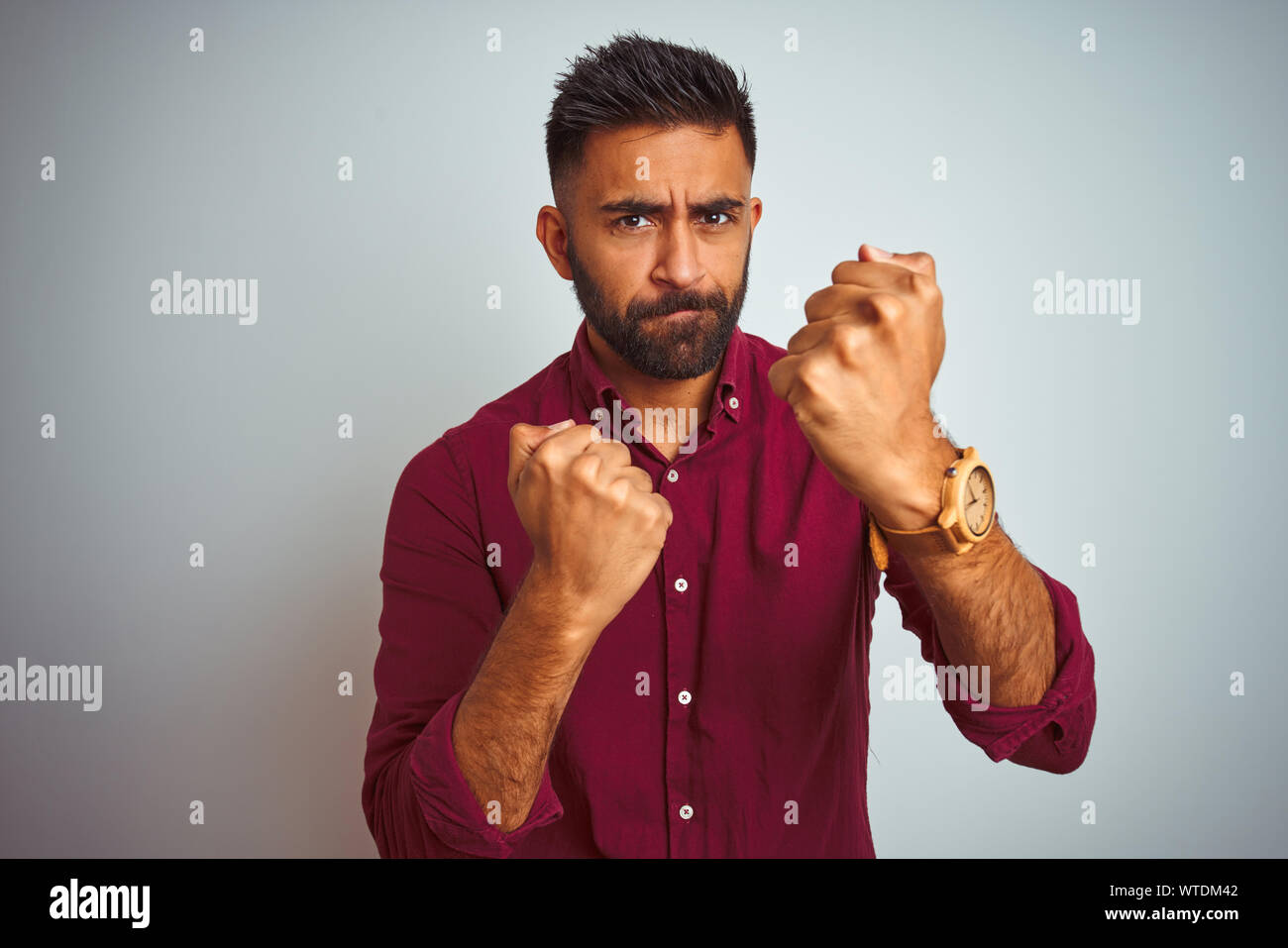 young-indian-man-wearing-red-elegant-shirt-standing-over-isolated-grey-background-ready-to-fight-with-fist-defense-gesture-angry-and-upset-face-afra-WTDM42.jpg
