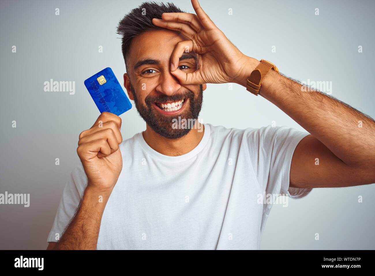 Young indian customer man holding credit card standing over isolated ...