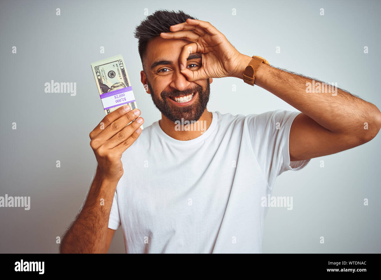 Young indian man holding dollars standing over isolated white ...