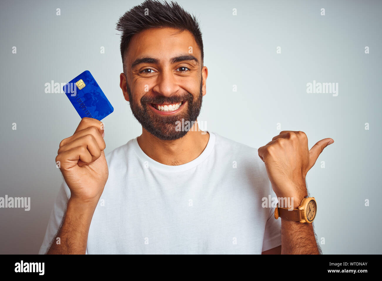 Young indian customer man holding credit card standing over isolated ...