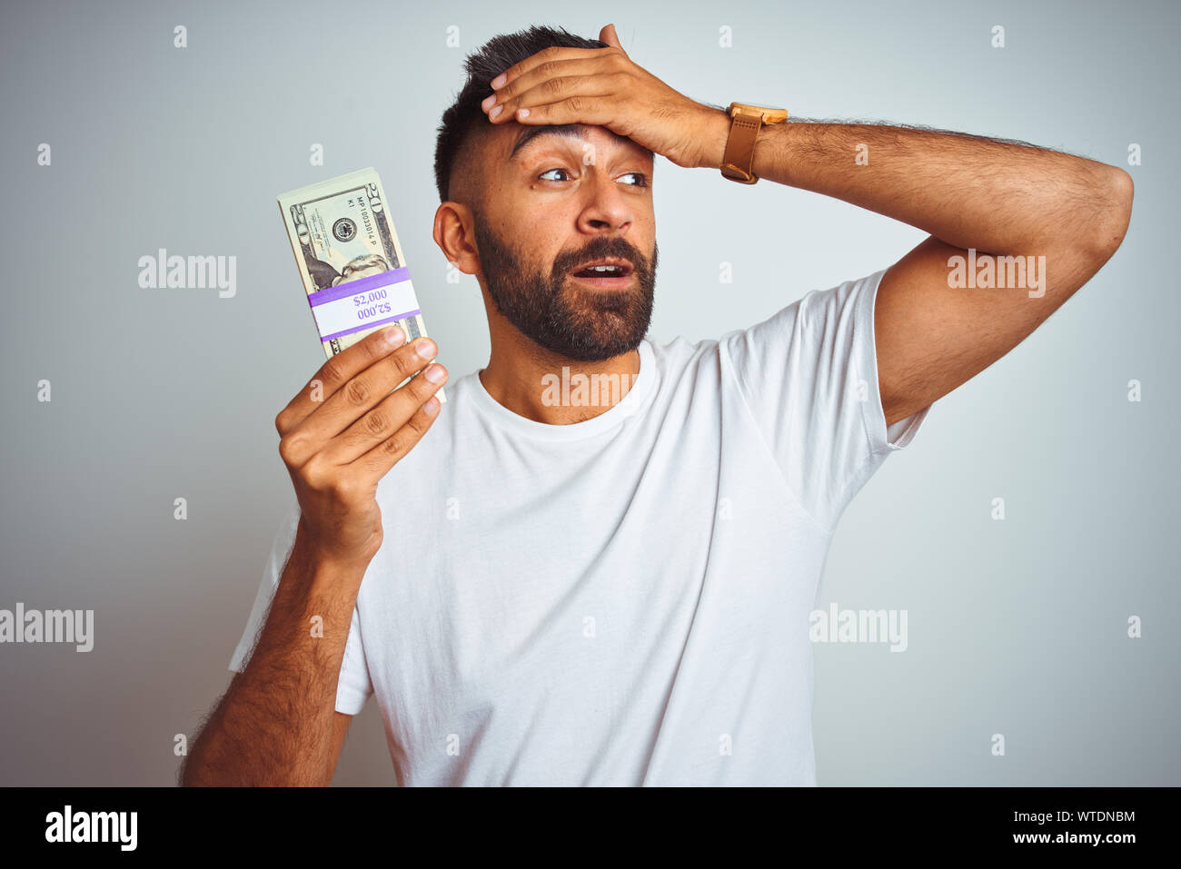 Young indian man holding dollars standing over isolated white ...