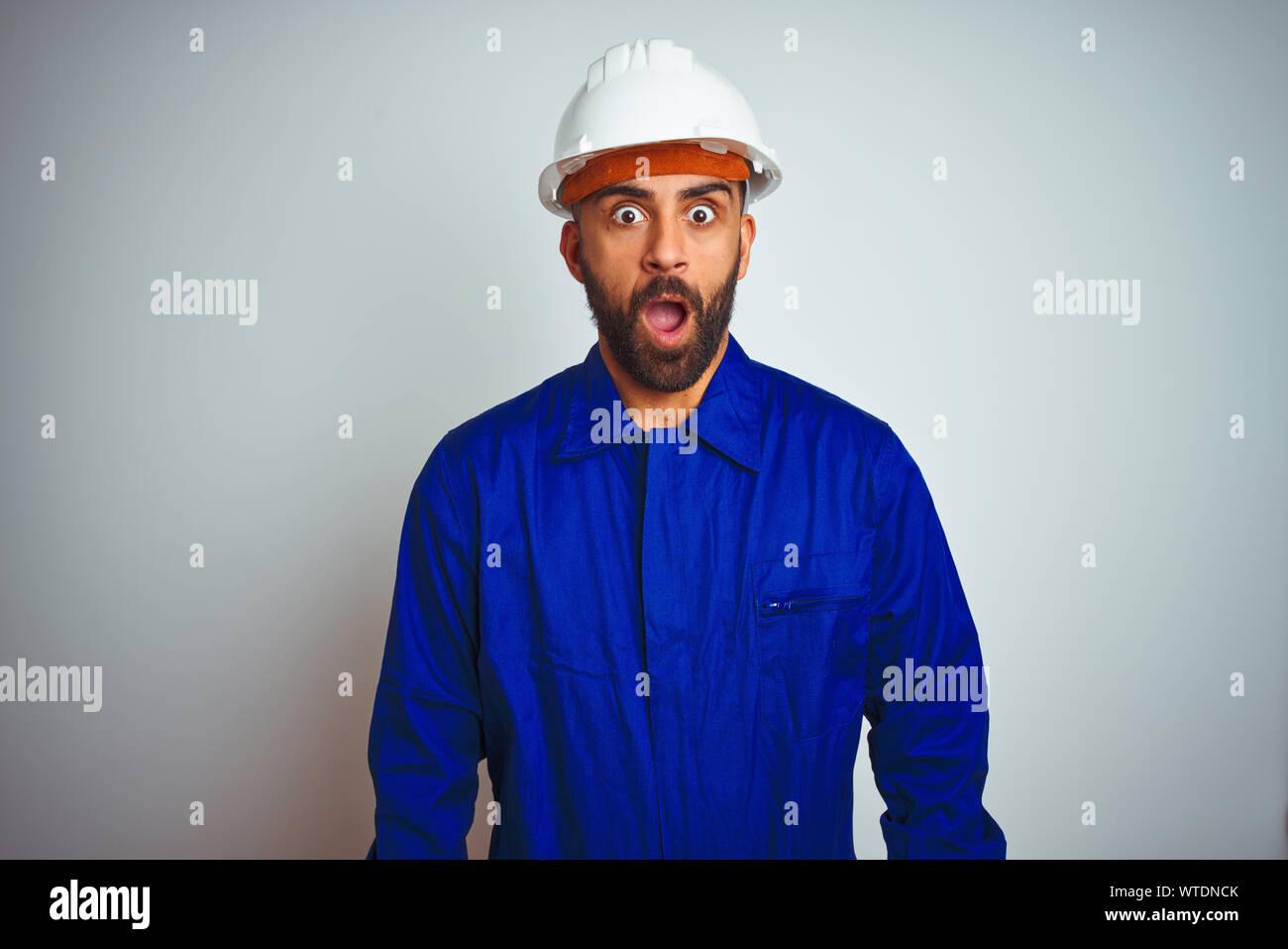 Handsome indian worker man wearing uniform and helmet over isolated ...