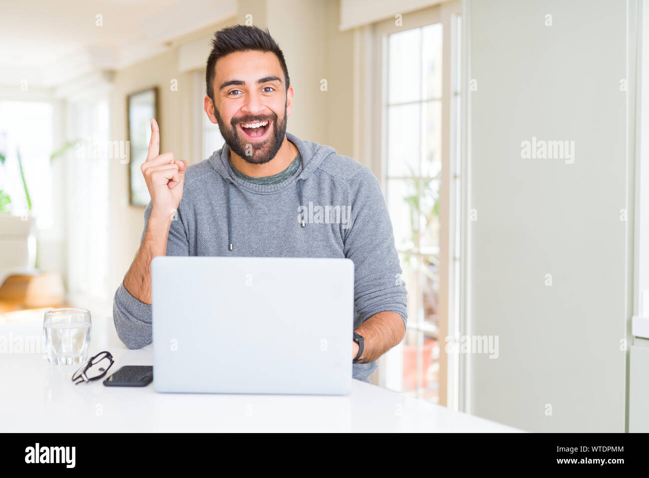 Handsome hispanic man working using computer laptop surprised with an ...