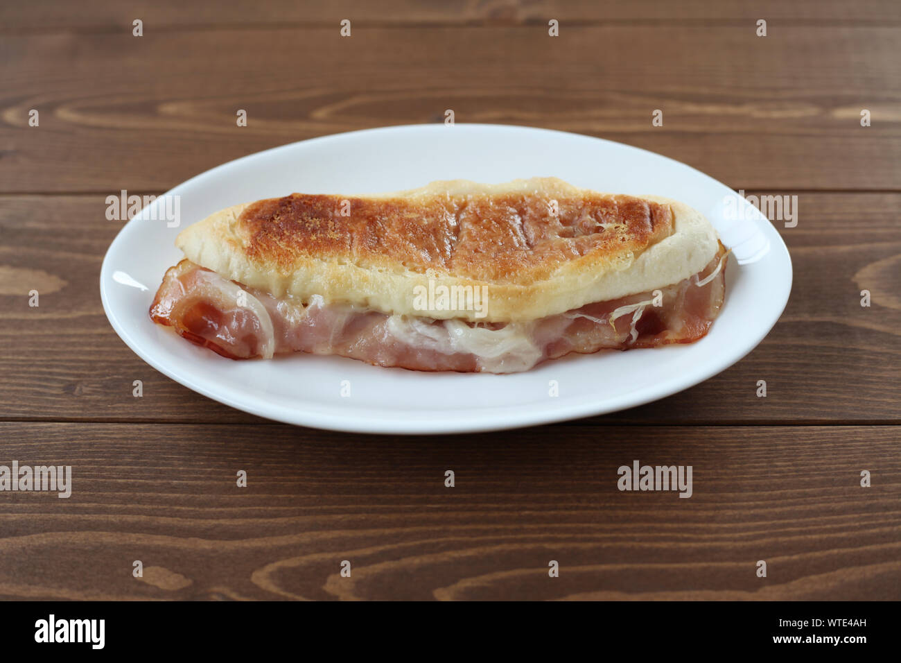 panino sandwich with bacon ham on plate closeup isolated on table Stock Photo