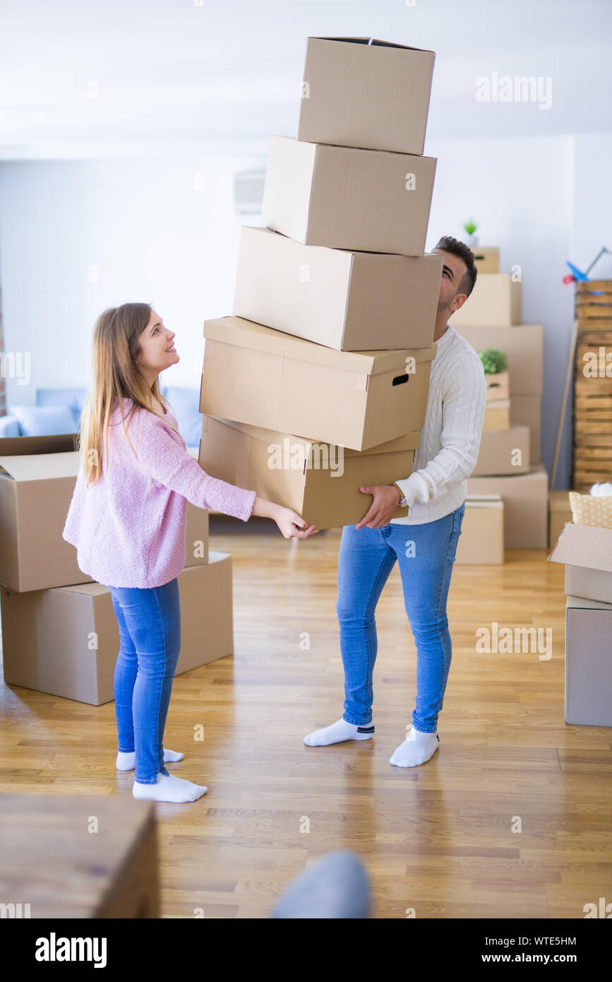 Young couple moving to a new house holding cardboard boxes worried ...