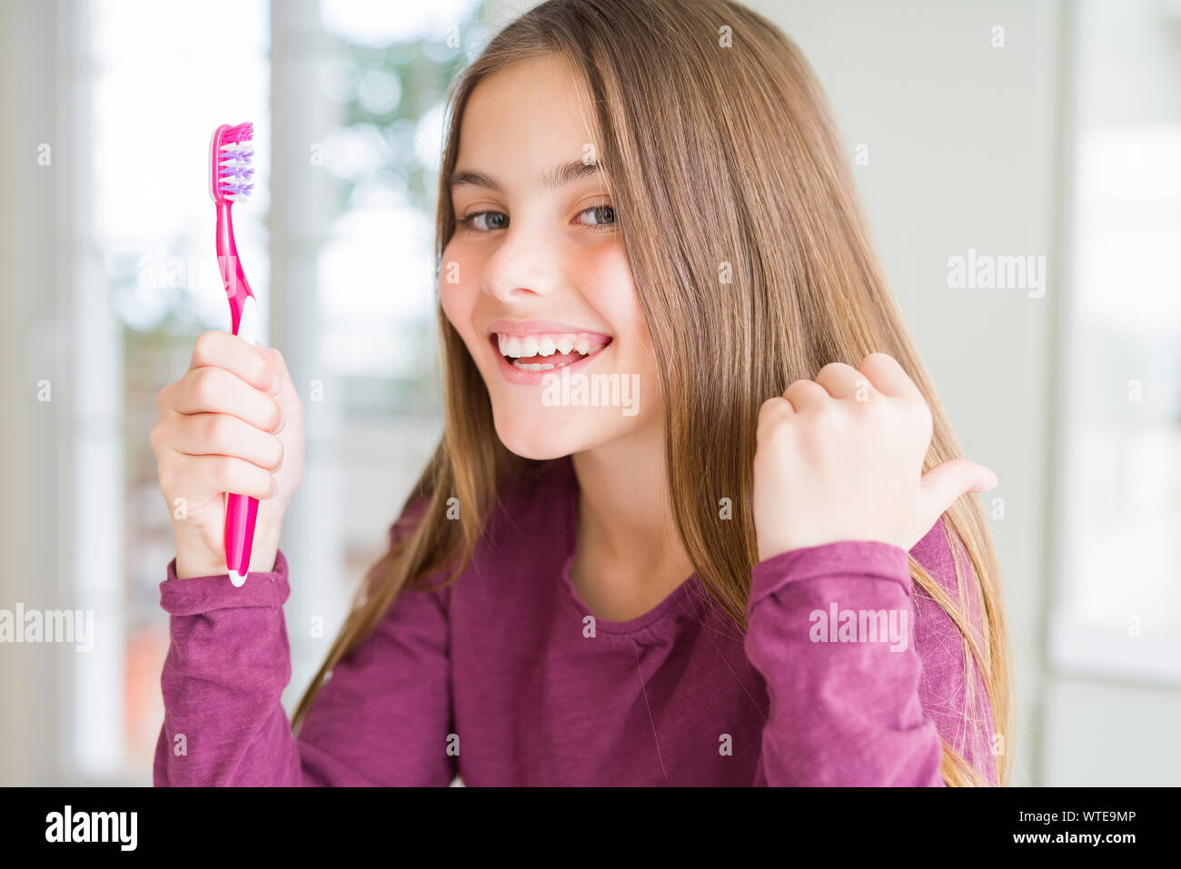 Beautiful young girl kid holding pink dental toothbrush pointing and ...