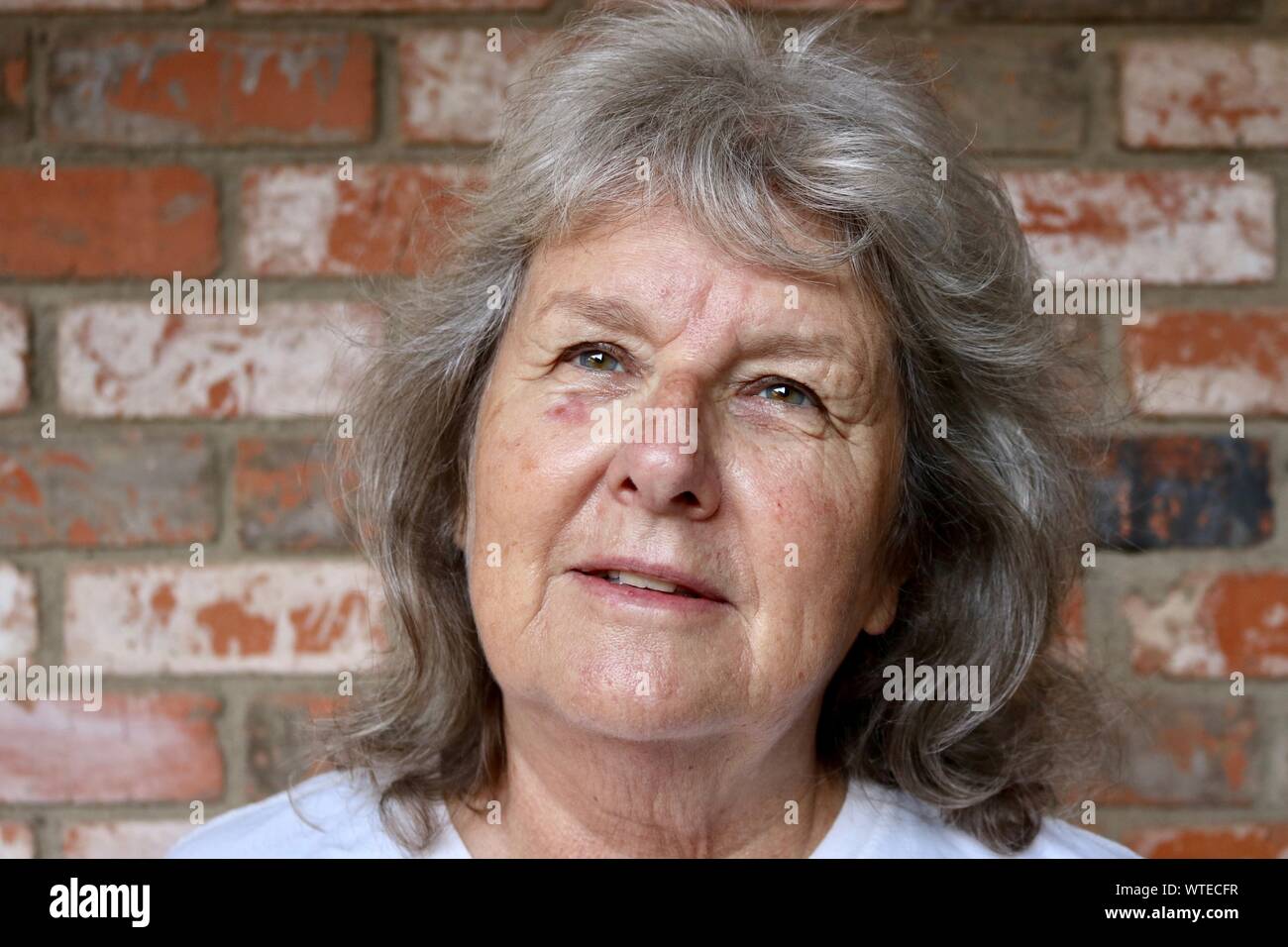 Portrait of an older woman with grey hair looking hopeful Stock Photo