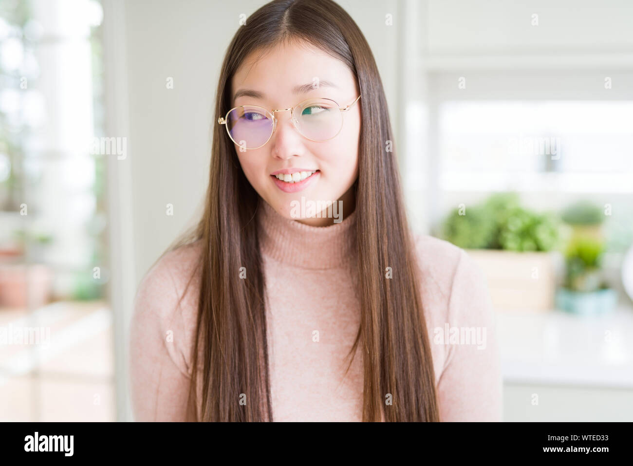 Beautiful Asian woman wearing glasses smiling looking side and staring ...