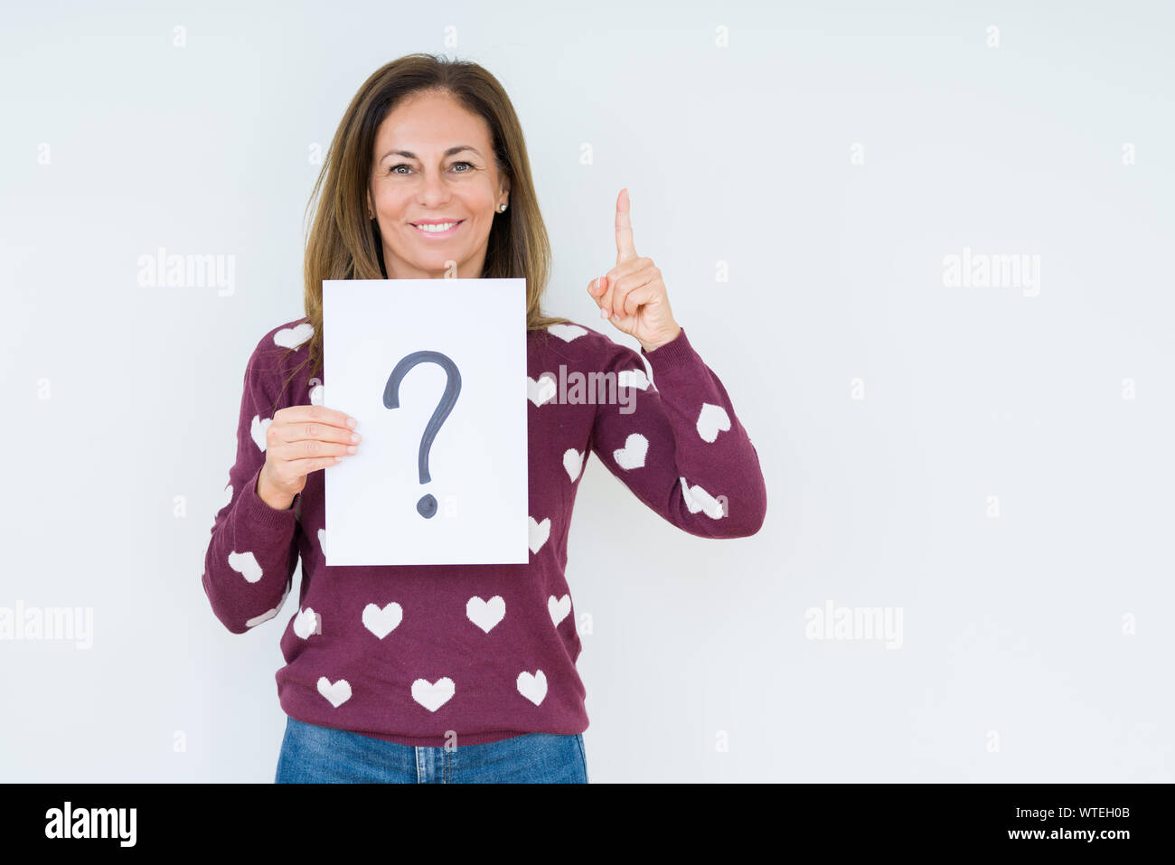 Middle age woman thinking and holding paper with question mark symbol ...