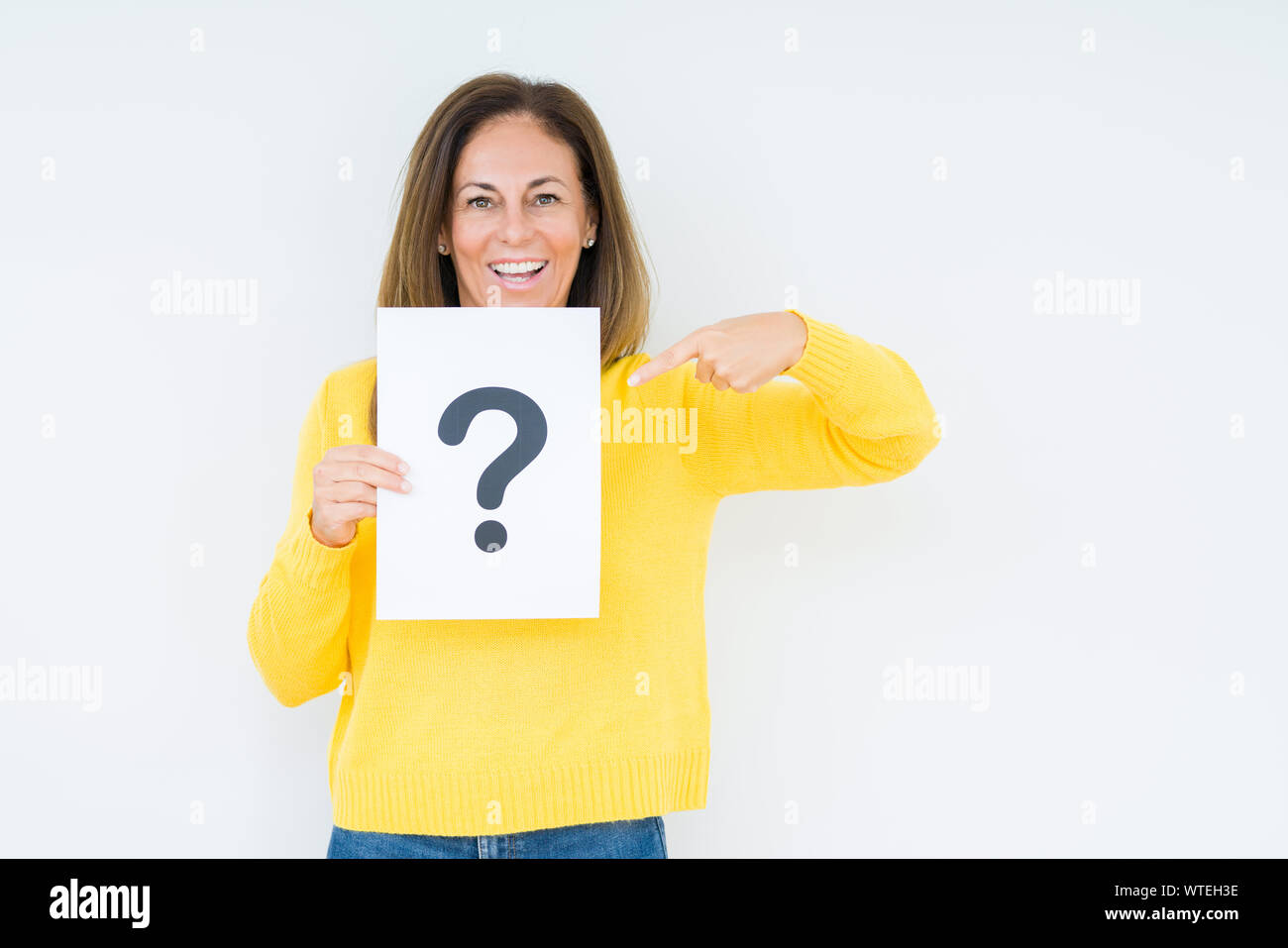 Middle age woman thinking and holding paper with question mark symbol ...