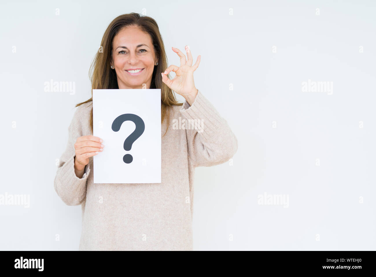 Middle age woman thinking and holding paper with question mark symbol ...