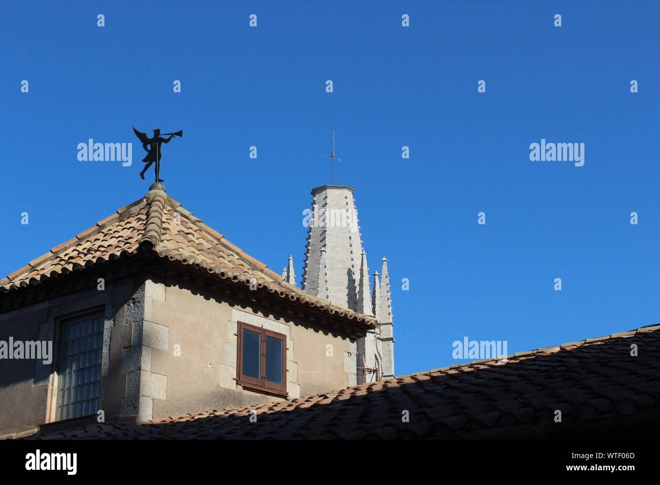 Low Angle View Of Weather Vane On Roof By Esglesia De Sant Feliu Against Clear Blue Sky Stock Photo