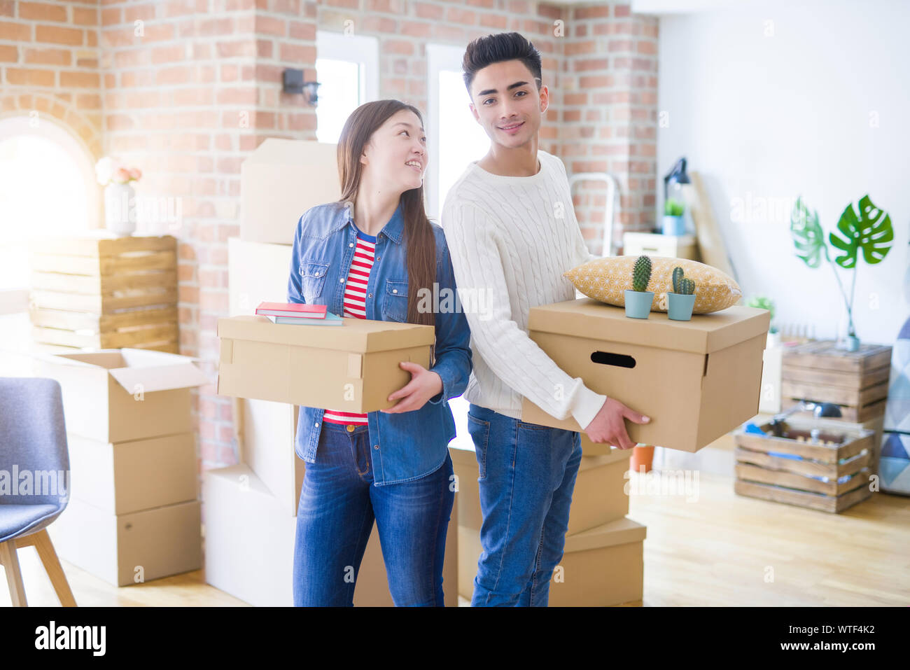 Beautiful young asian couple looking happy holding cardboard boxes ...