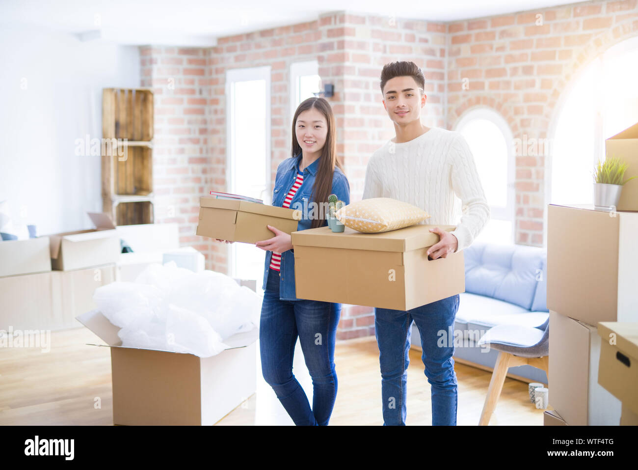 Beautiful young asian couple looking happy holding cardboard boxes ...