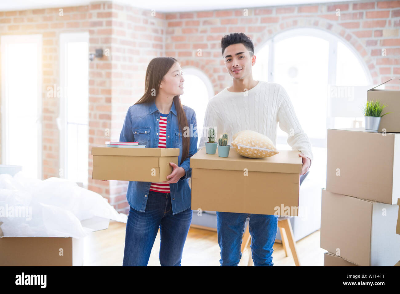 Beautiful young asian couple looking happy holding cardboard boxes ...