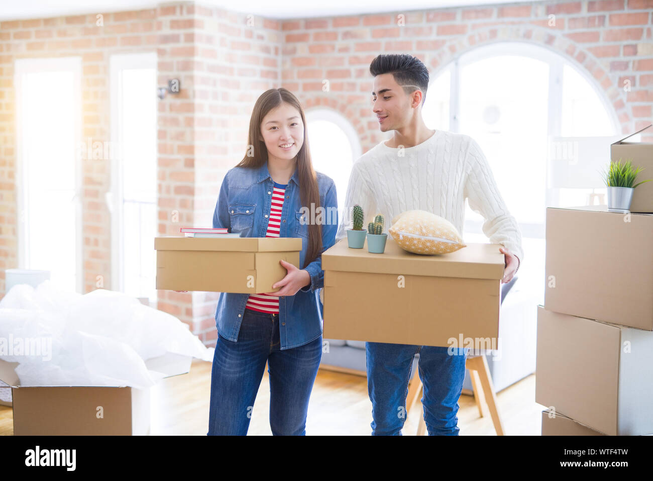 Beautiful young asian couple looking happy holding cardboard boxes ...