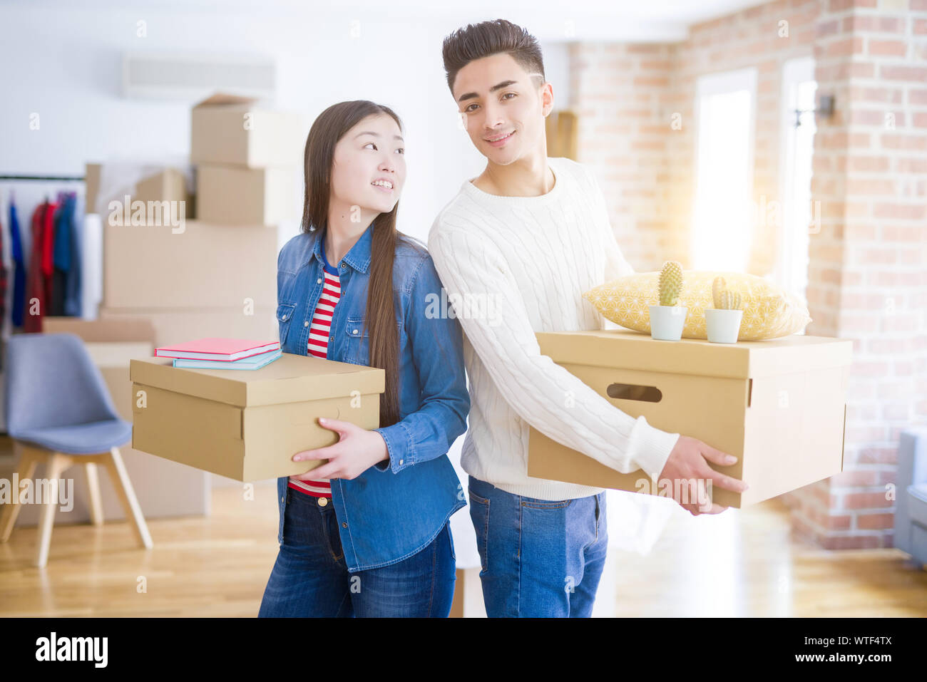 Beautiful young asian couple looking happy holding cardboard boxes ...