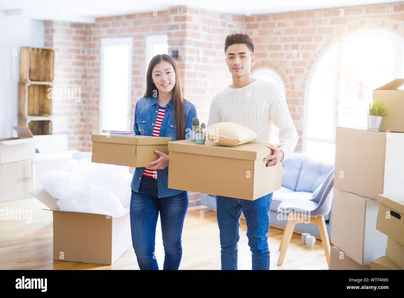 Beautiful young asian couple looking happy holding cardboard boxes ...