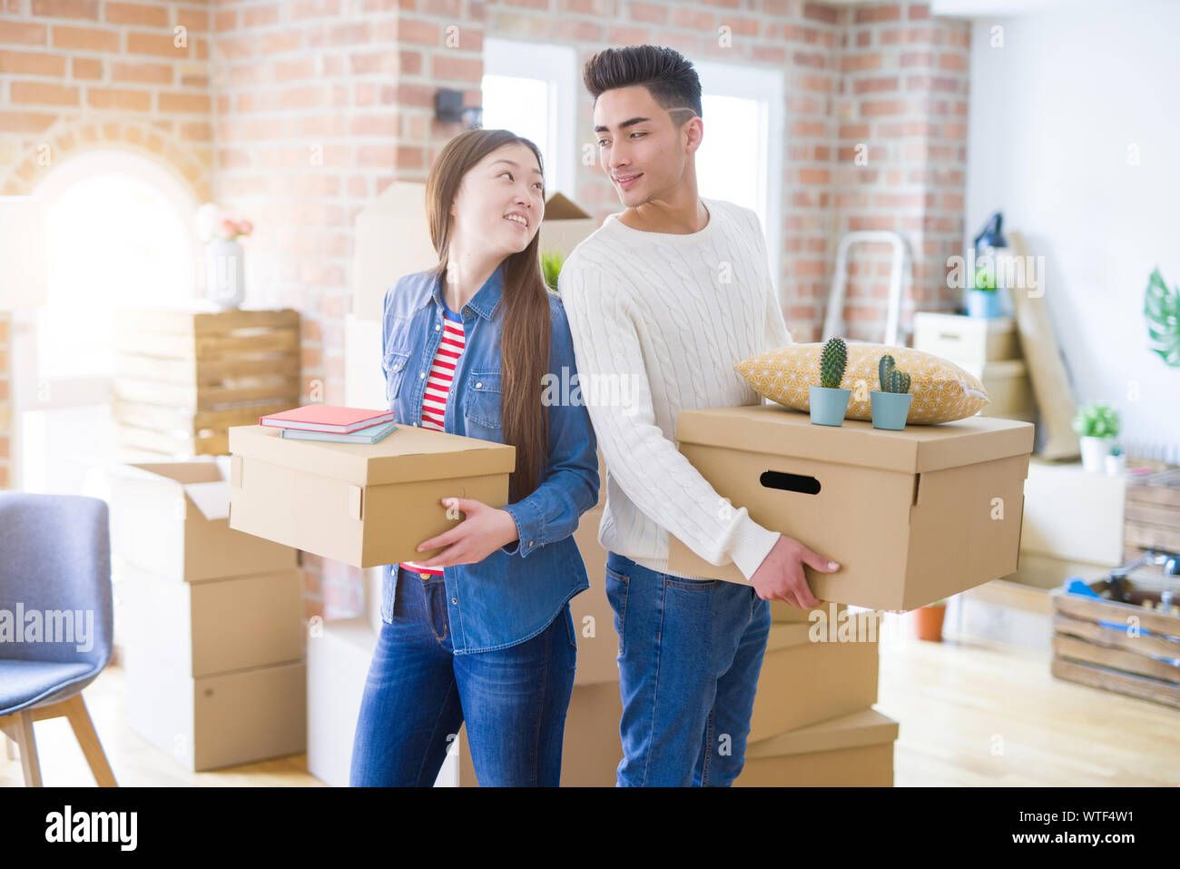 Beautiful young asian couple looking happy holding cardboard boxes ...