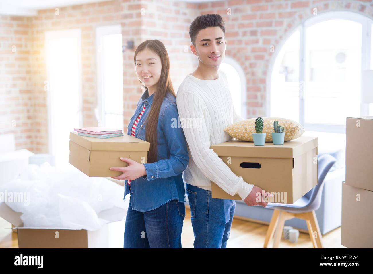 Beautiful young asian couple looking happy holding cardboard boxes ...