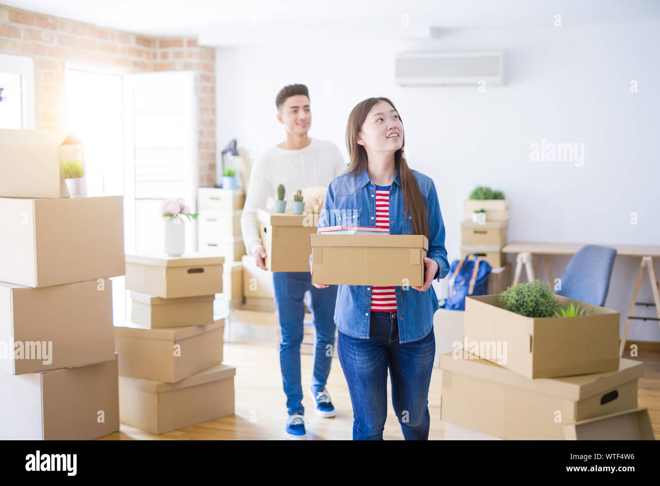 Beautiful young asian couple looking happy holding cardboard boxes ...