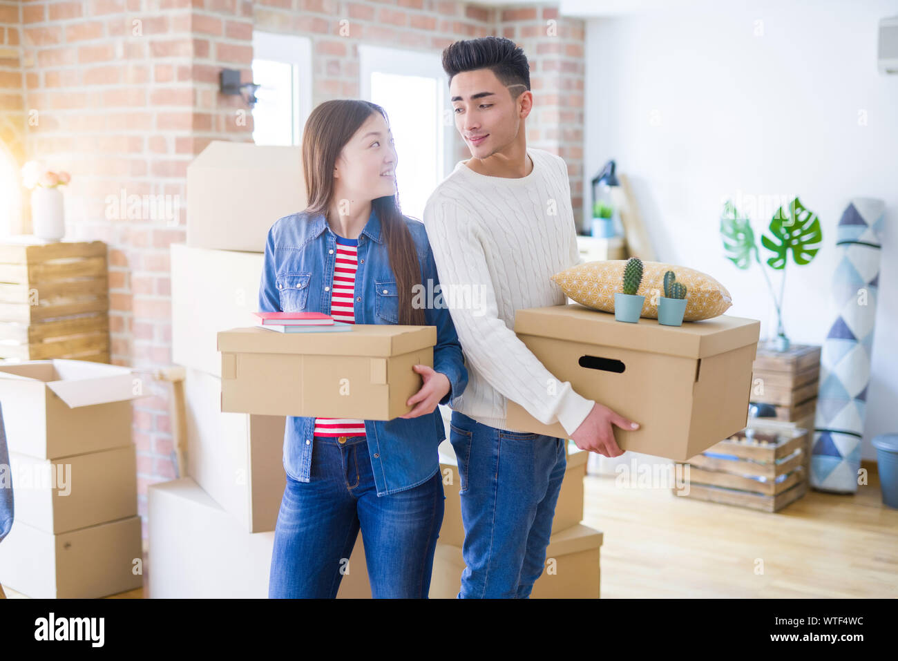Beautiful young asian couple looking happy holding cardboard boxes ...