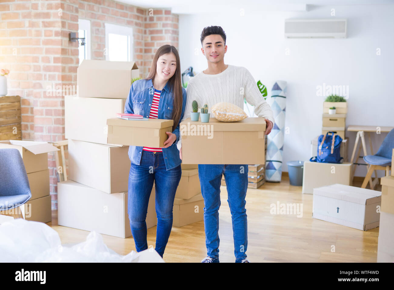 Beautiful young asian couple looking happy holding cardboard boxes ...