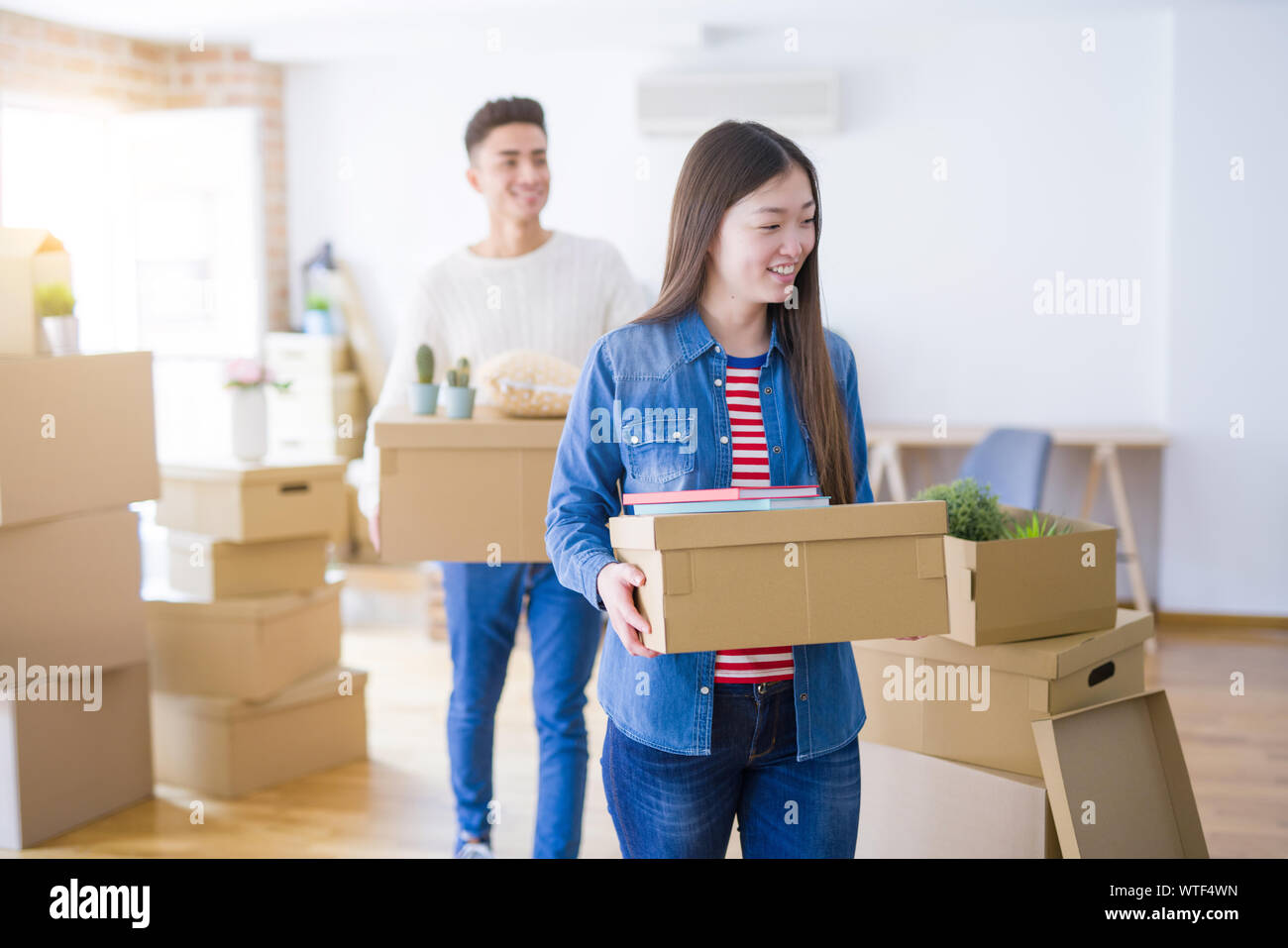 Beautiful young asian couple looking happy holding cardboard boxes ...