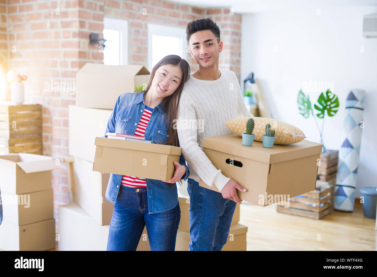 Beautiful young asian couple looking happy holding cardboard boxes ...