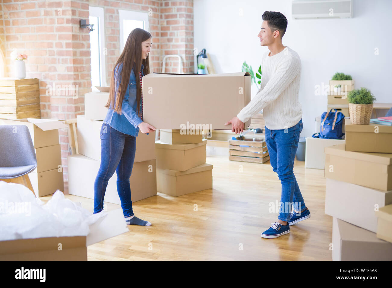 Beautiful young asian couple looking happy, holding a big cardboard box ...