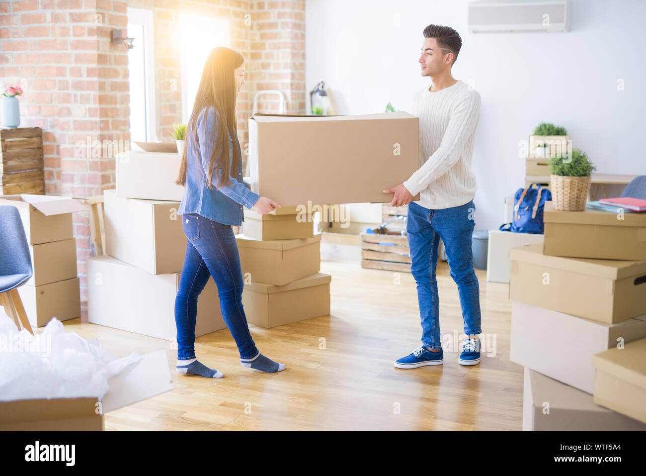 Beautiful young asian couple looking happy, holding a big cardboard box ...