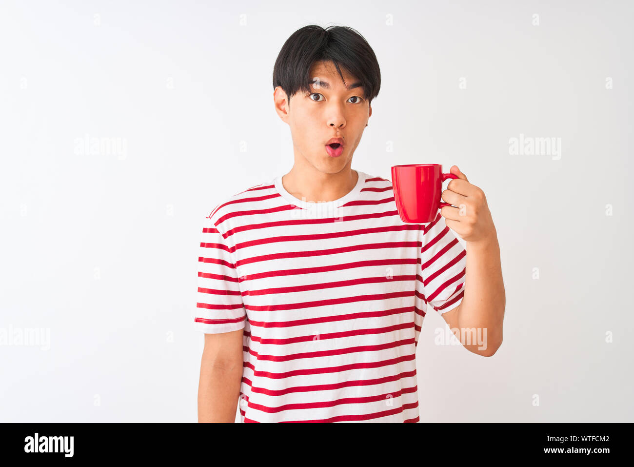 Young chinese man drinking a cup of coffee standing over isolated white