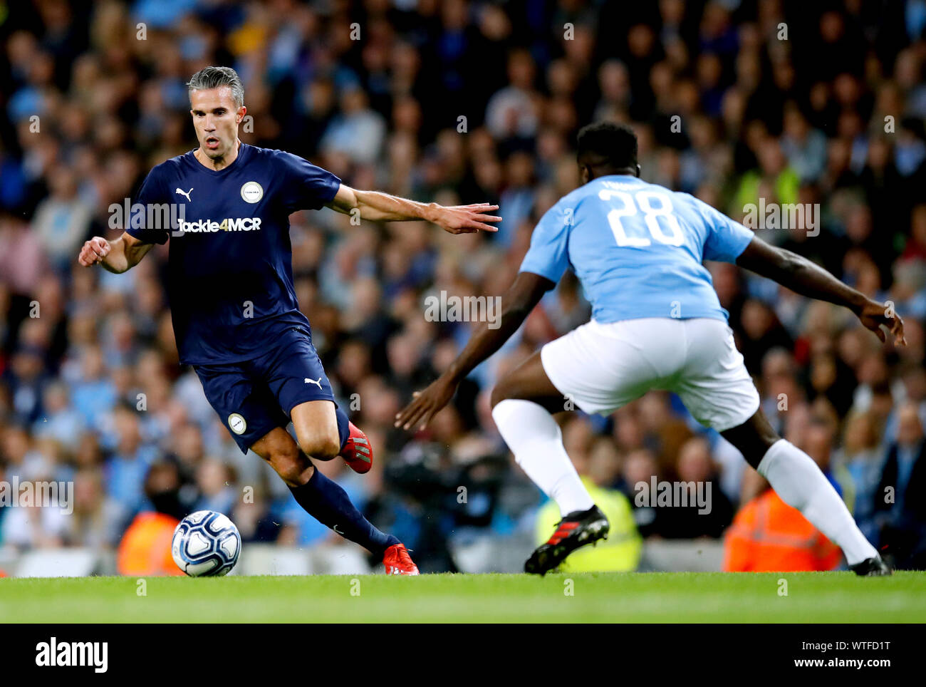 Premier League All Stars XI Robin van Persie (left) and Manchester City Legend's Kolo Toure battle for the ball during the Vincent Kompany Testimonial at the Etihad Stadium, Manchester. Stock Photo