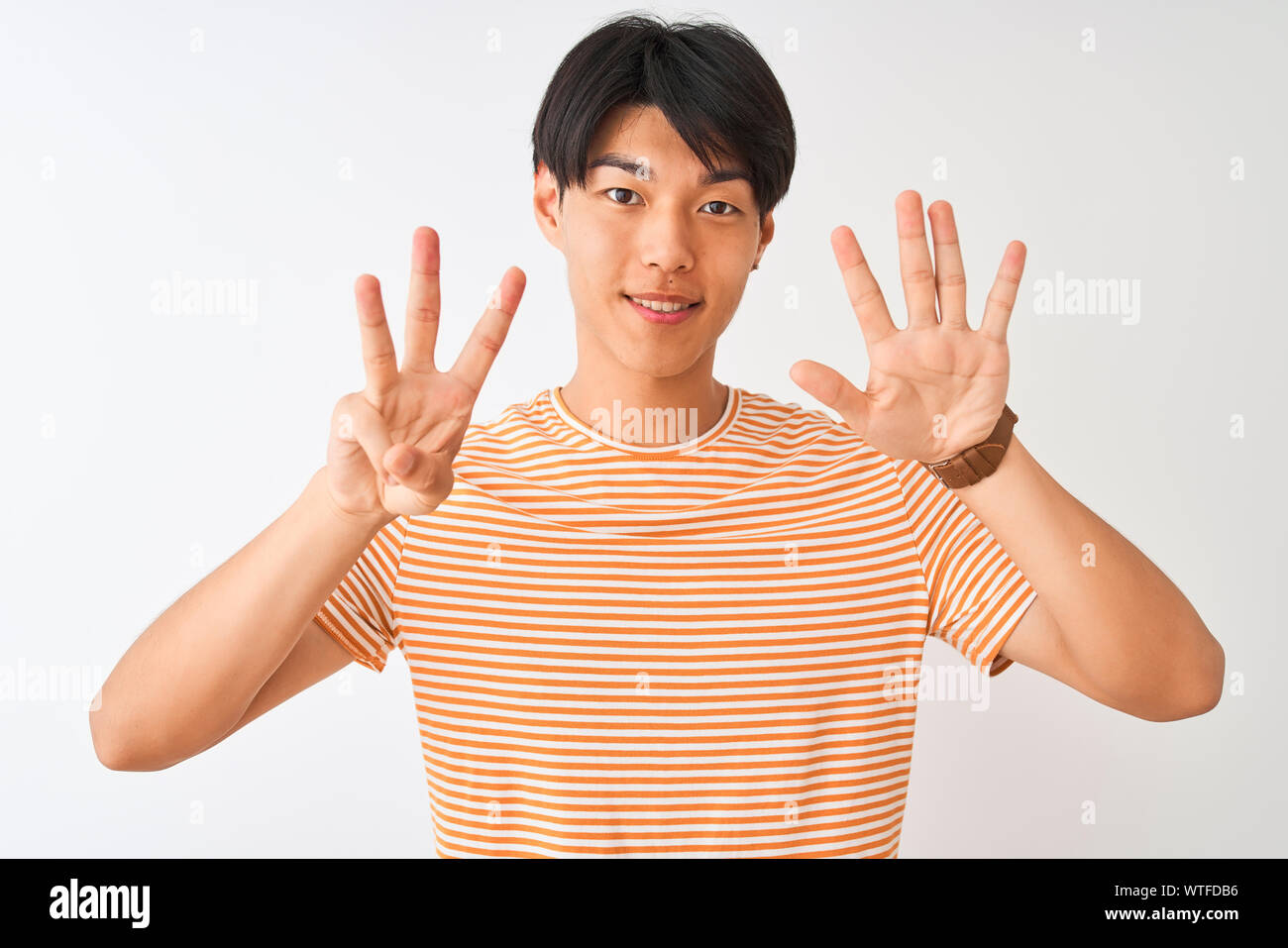 Young chinese man wearing casual striped t-shirt standing over isolated ...