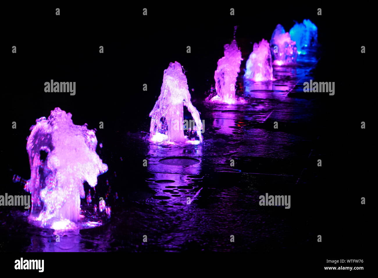 Real coloured water fountains in lines on the black background Stock Photo