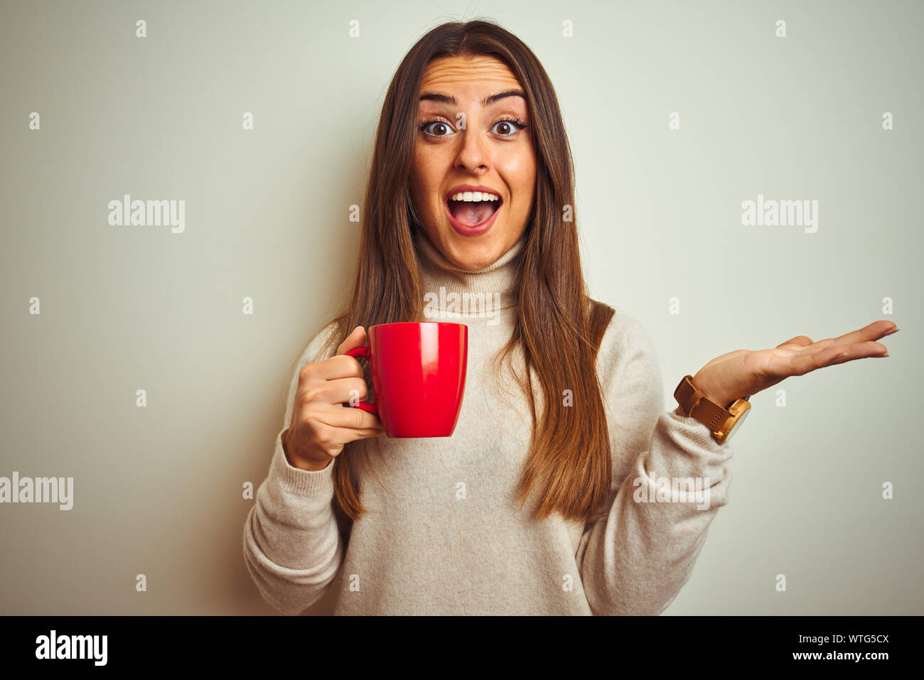 Young beautiful woman drinking red cup of coffee standing over isolated ...