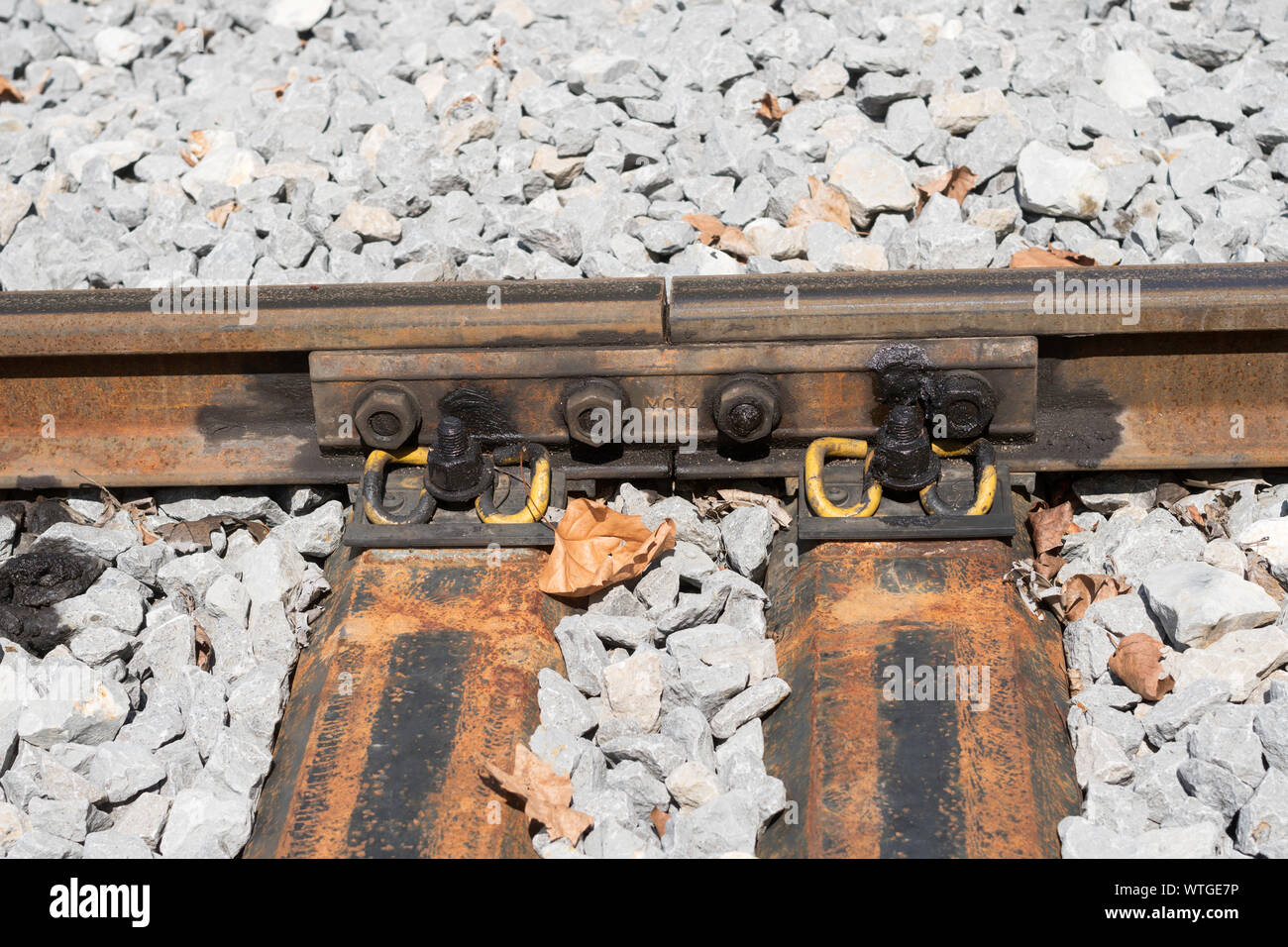 Rail joint with 4 bolt fishplate and elastic railway clips over metal sleepers on metre gauge railway in France, Europe Stock Photo