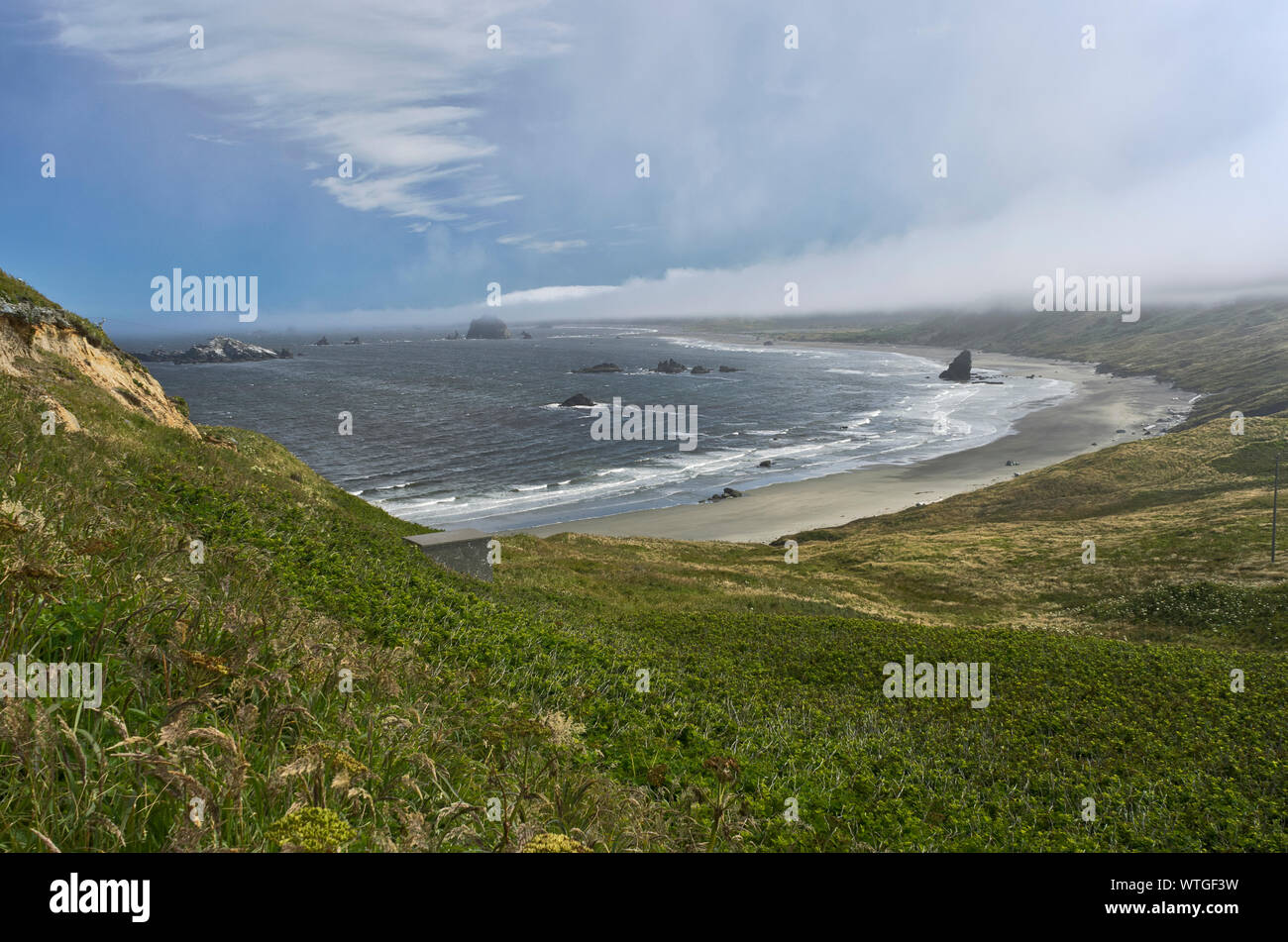 Wide view of sea stacks and sand beach off of Cape Blanco, with fog descending, at Cape Blanco State Park, Oregon Stock Photo