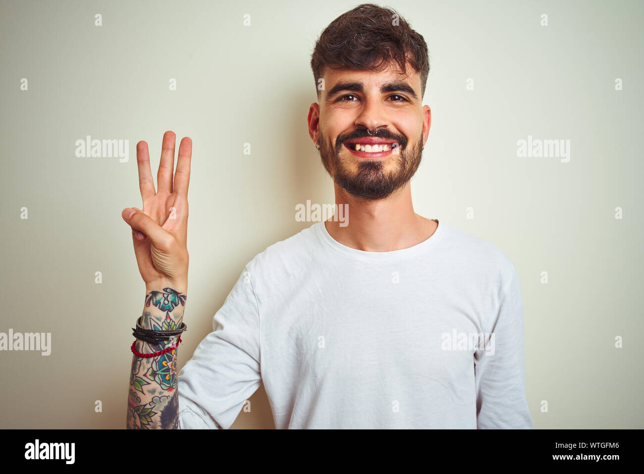 Young man with tattoo wearing t-shirt standing over isolated white ...