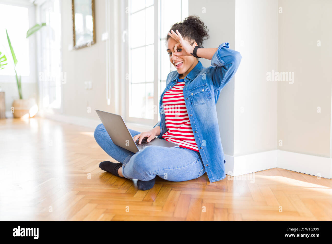 Young african american woman sitting on the floor using computer laptop ...