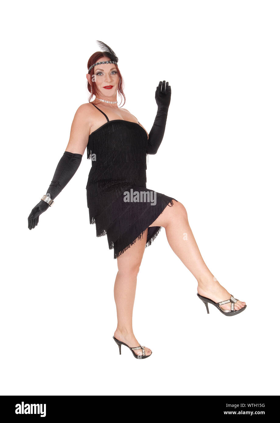 A gorgeous woman in a black dress of the 20 century and long cloves dancing in the studio, isolated for white background Stock Photo