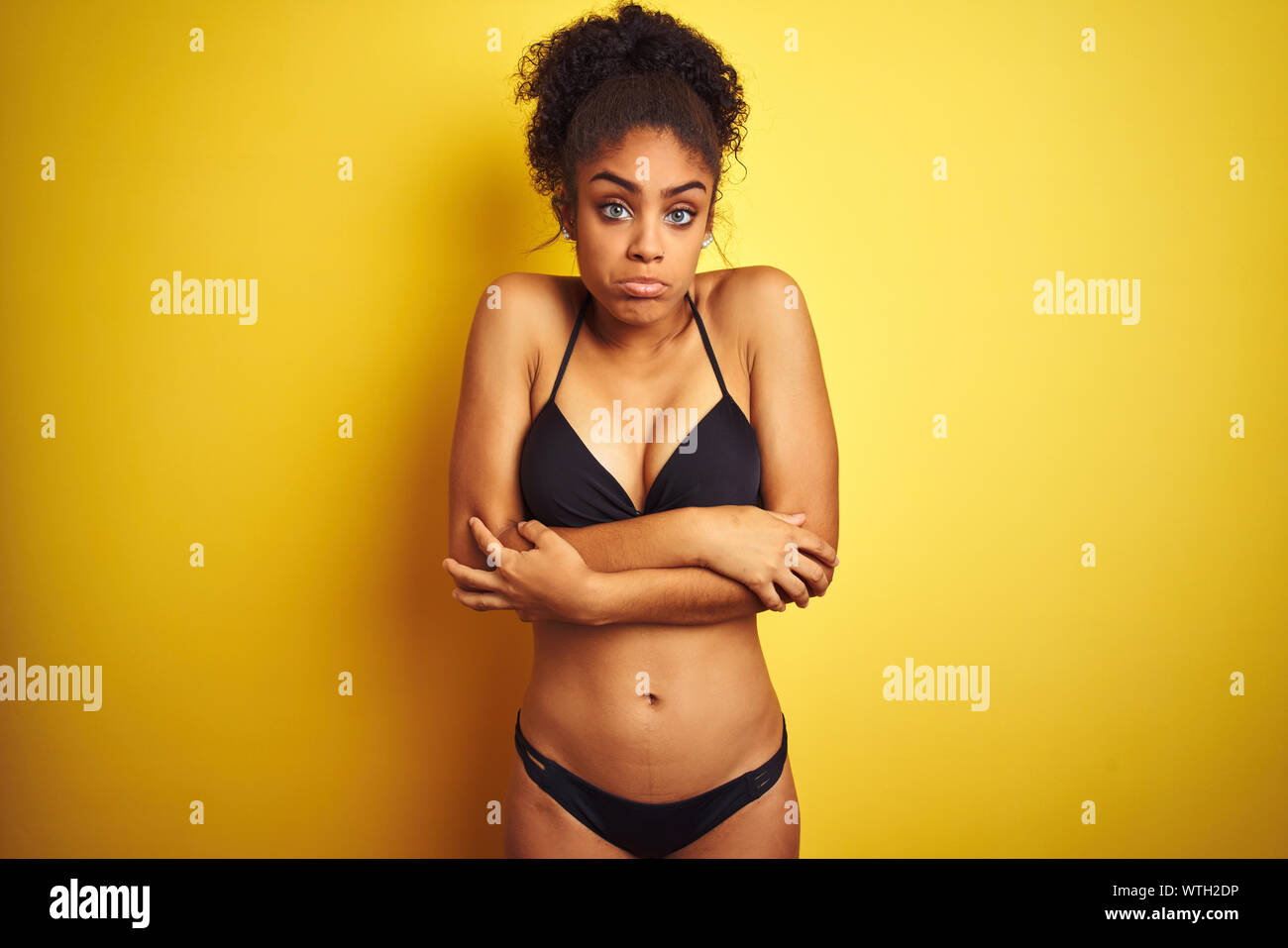 African american woman on vacation wearing bikini standing over isolated  yellow background shaking and freezing for winter cold with sad and shock  exp Stock Photo - Alamy