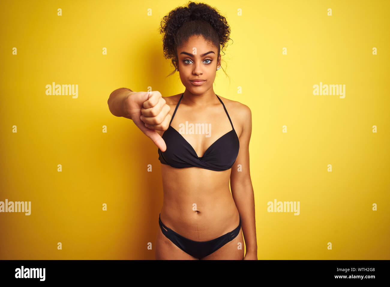 African american woman on vacation wearing bikini standing over isolated  yellow background looking unhappy and angry showing rejection and negative  wi Stock Photo - Alamy