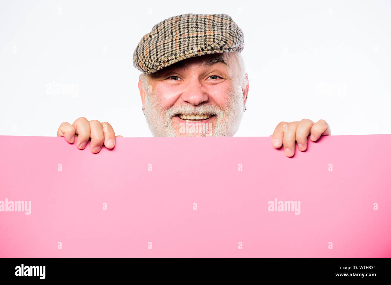 Senior bearded man peeking out of banner place information. Announcement concept. Public information. Advertisement elderly people. Pensioner hold poster information copy space. Weekend entertainment. Stock Photo
